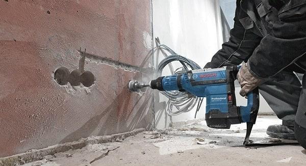 Máy khoan Bosch có búa đang khoan tường gạch để thi công điện âm